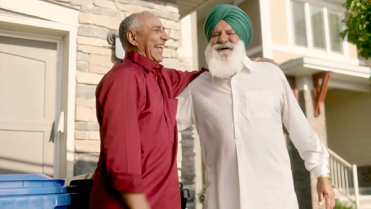 Two neighbours with arms around each other in front of a house