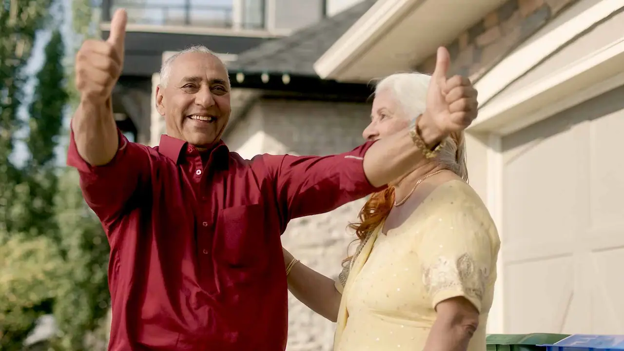 A man and woman giving each other a proud thumbs-up in the driveway